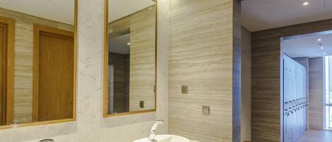 A modern bathroom with two sinks, a large mirror, and a wooden bench.
