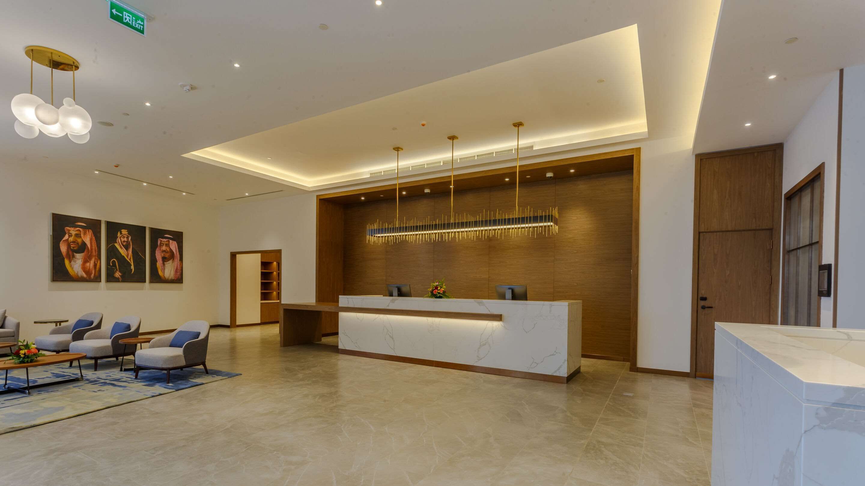 Un espace d’accueil moderne, doté d’un comptoir de réception en marbre, d’un mur d’accent en bois et d’un coin salon avec des canapés et une table basse.