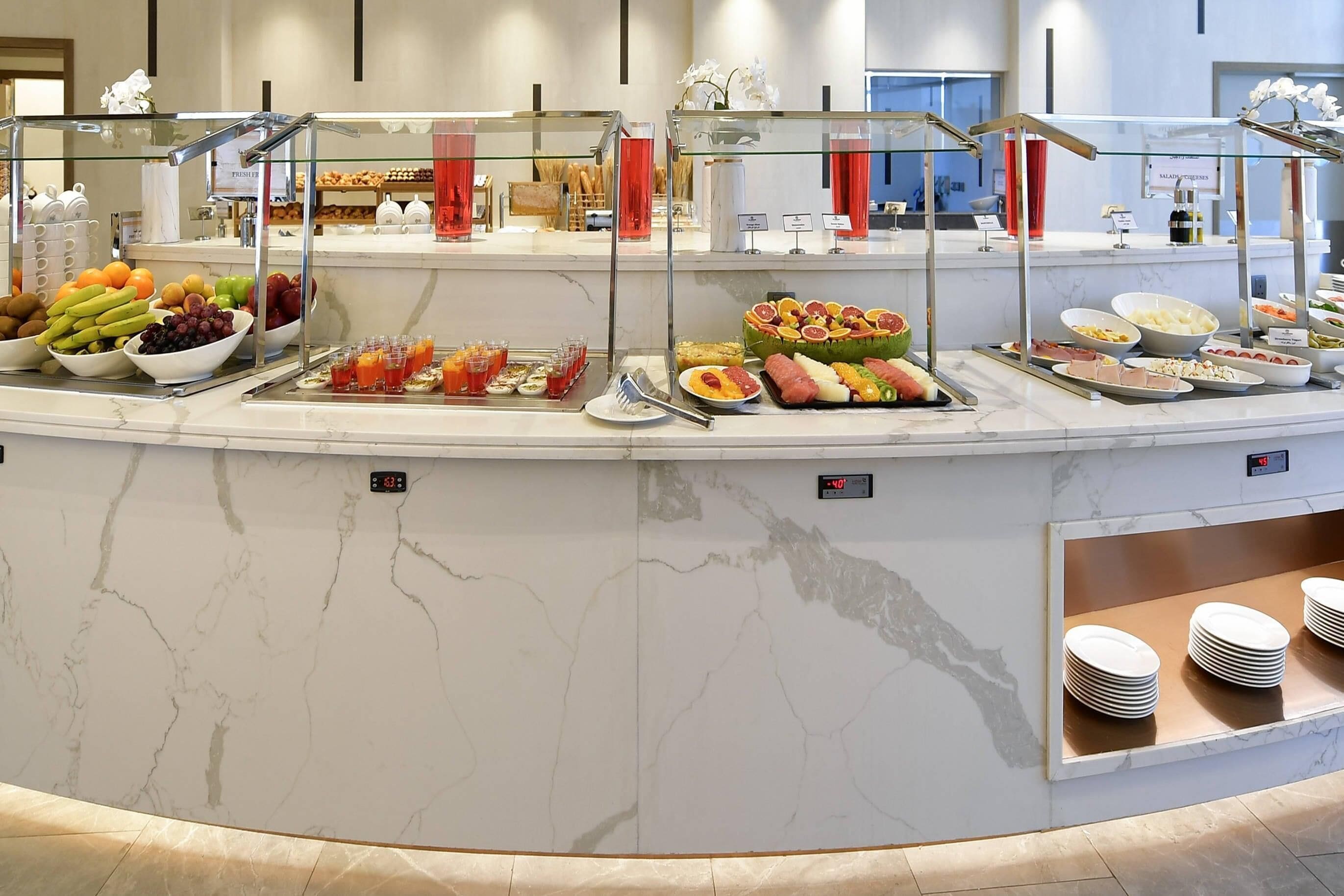 Un buffet proposant divers plats et une horloge indiquant 9 h 07.