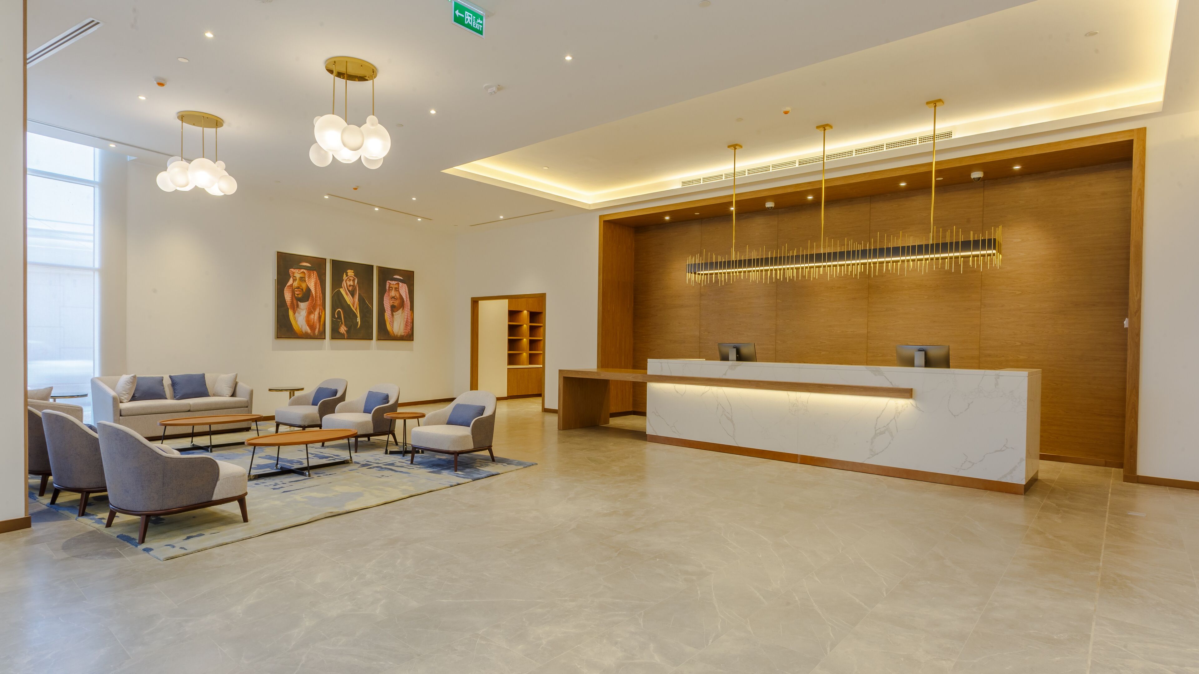 A modern hotel lobby with a reception desk, seating area, and artwork on the walls.