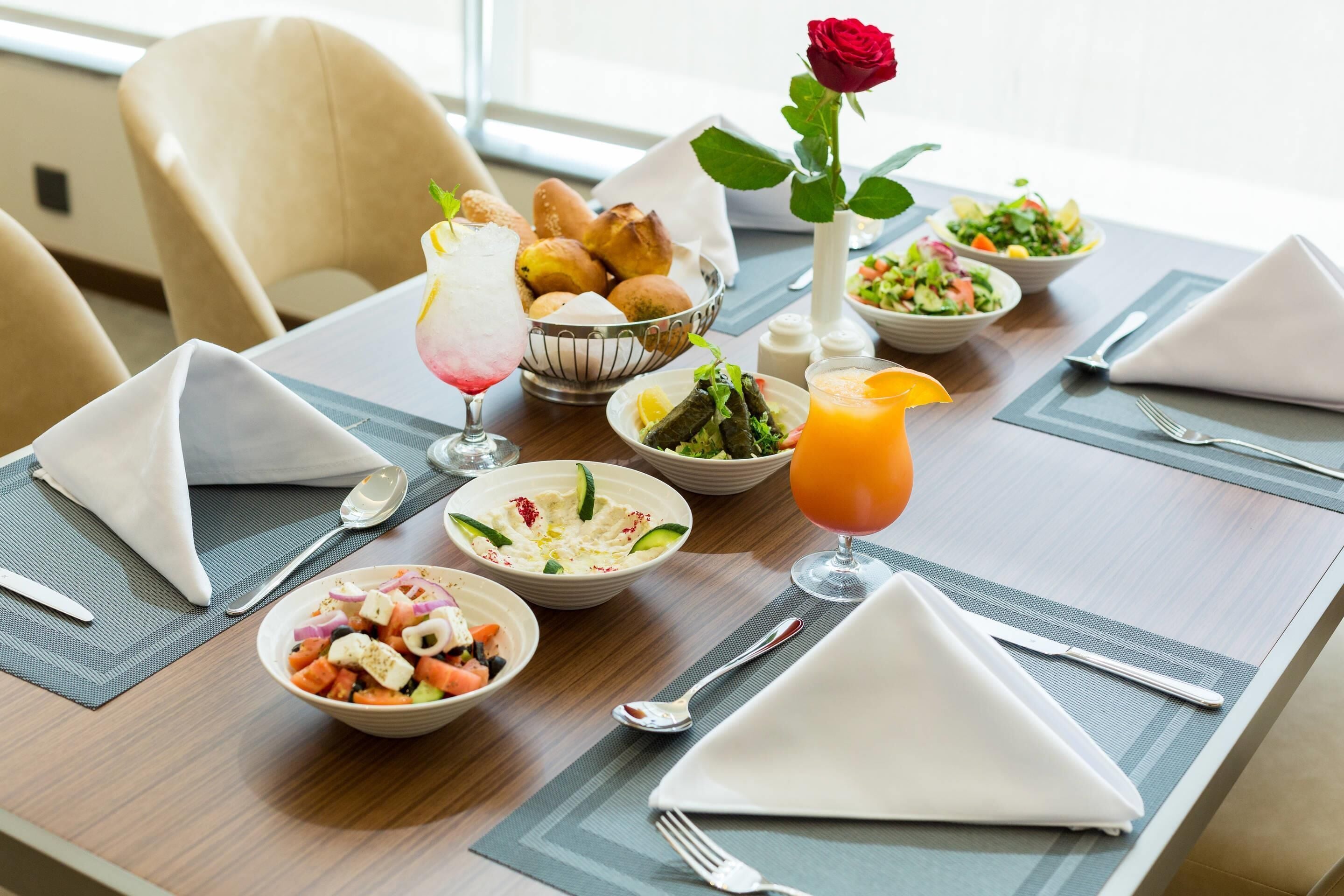 A dining table set with various dishes, including salads, a fruit drink, and bread.