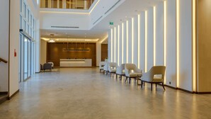 Un vestíbulo amplio con mostrador de recepción, zona de estar y escalera.