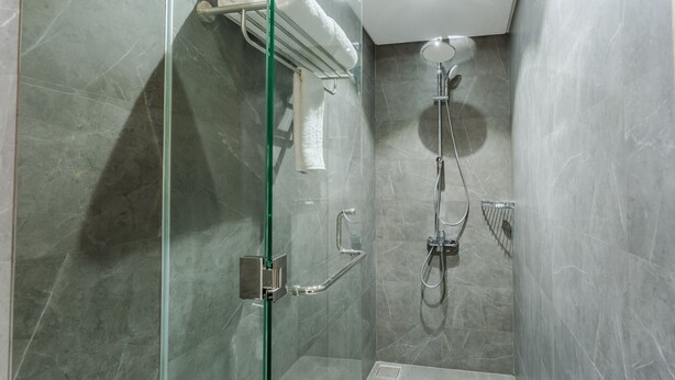 Un espace douche moderne doté d’une porte en verre, d’un pommeau de douche à main et d’un robinet mural.