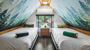Une chambre mansardée chaleureuse, avec deux lits, un banc en bois et une vue par la fenêtre.