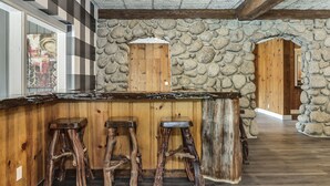 Un coin bar au style rustique, avec des tabourets en bois, un mur en pierre et des portes en bois.