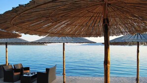 A beachside lounge with thatched umbrellas, lounge chairs, and a small table. - Fantastic beachfront apartment with private balcony on the Adriatic.Top location (Seget Donji)