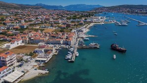 An aerial view of a coastal town with a marina, residential buildings, and a mountainous backdrop. - Fantastic beachfront apartment with private balcony on the Adriatic.Top location (Seget Donji)