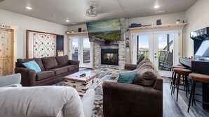 A spacious living room with a fireplace, a large window, and a gaming table. - Crown Jewel | Table Rock Lake Views | Sleeps 24 | Near Silver Dollar City (Indian Point)