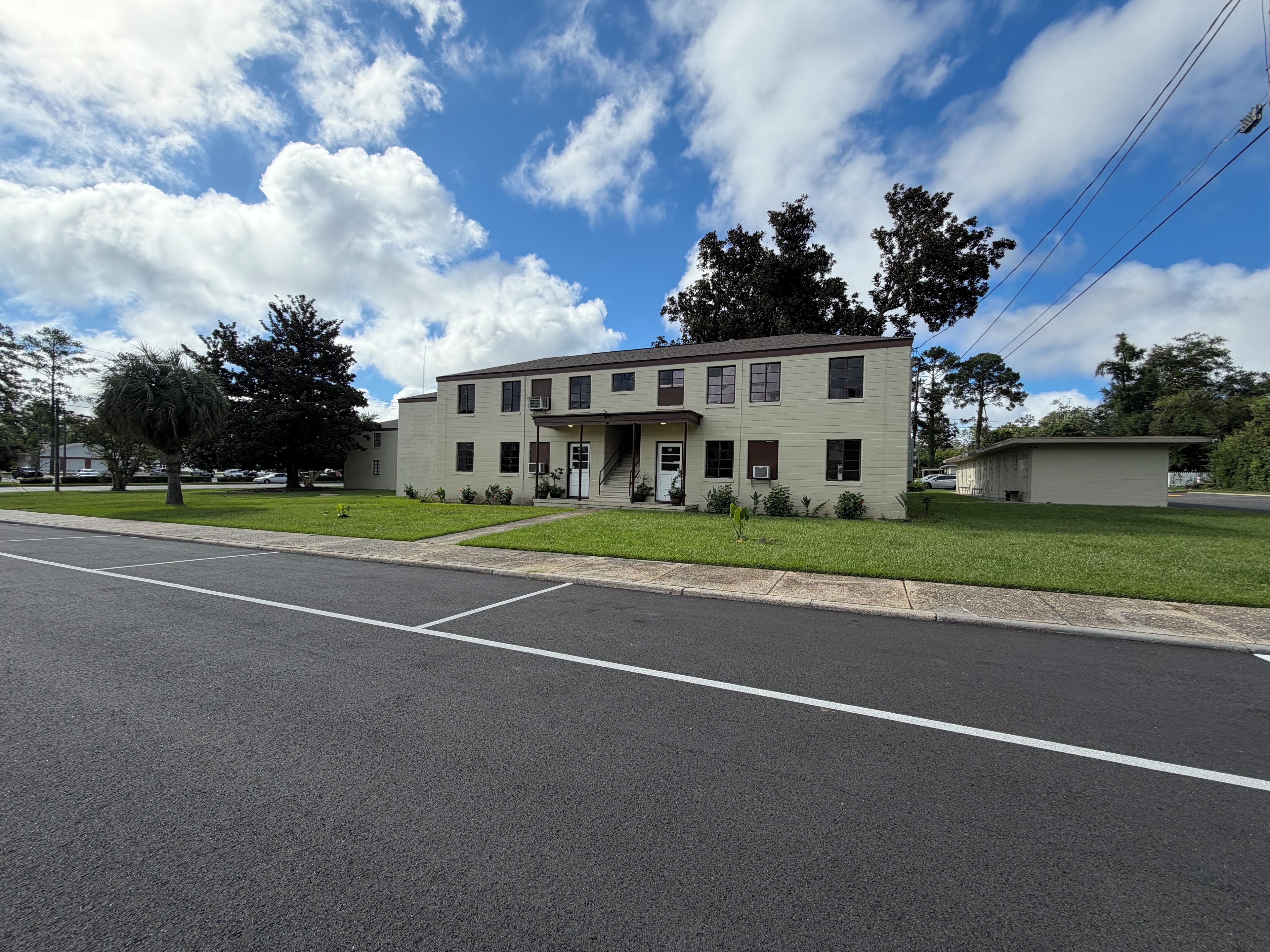 A two-story building with a flat roof, a front entrance with a door, and a small porch area.
