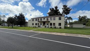 A two-story building with a flat roof, a front entrance with a door, and a small porch area.