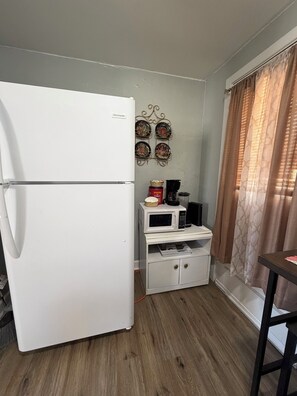 Une cuisine de taille réduite, avec un réfrigérateur blanc, un four à micro-ondes et un petit placard.