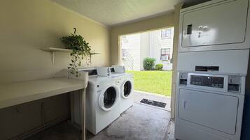 A laundry room with a washing machine, dryer, and stacked dryers.
