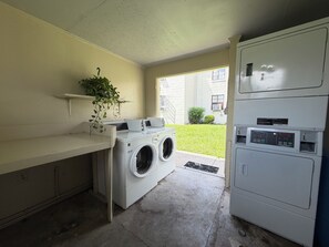Une buanderie équipée d’un lave-linge, d’un sèche-linge et de plusieurs sèche-linge superposés.