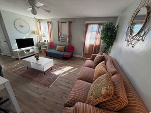 A living room with a sofa, TV, and a ceiling fan.