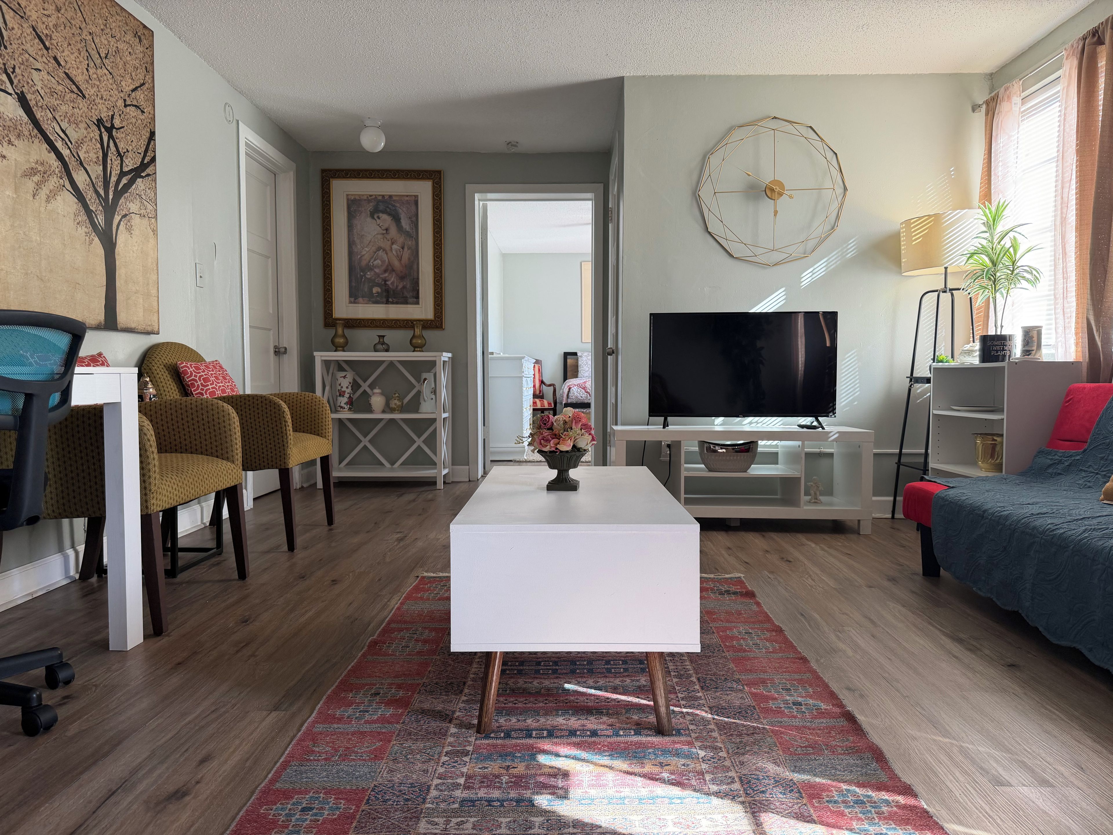 A living room with a white coffee table, a TV, a sofa, and a chair.