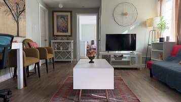 A living room with a white coffee table, a TV, a sofa, and a chair.