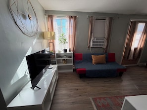 Un salon avec un téléviseur, un canapé et une plante.