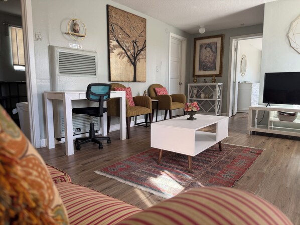 A living room with a sofa, a coffee table, a TV, a fireplace, and a painting on the wall.