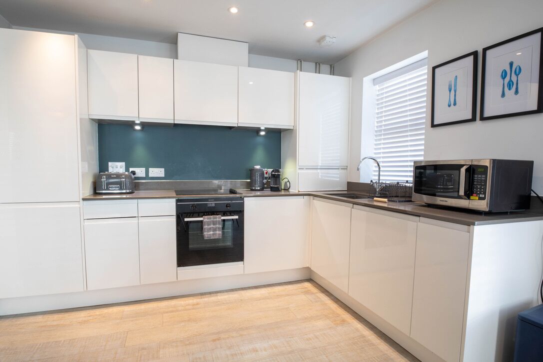 A modern kitchen with white cabinets, a stainless steel range, and a microwave.