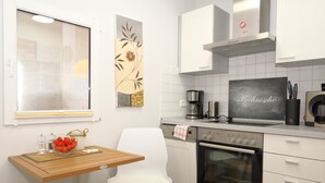 A modern kitchen with white cabinets, a stainless steel range hood, a coffee maker, and a dishwasher.