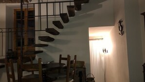 Un comedor con escalera espiral, sillas de madera, una mesa y una cesta.