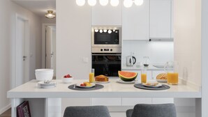 A modern kitchen with white cabinets, a built-in oven, and a dining area with a table set for breakfast.