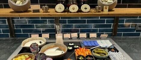 A buffet with various food items including fruits, vegetables, and dips.