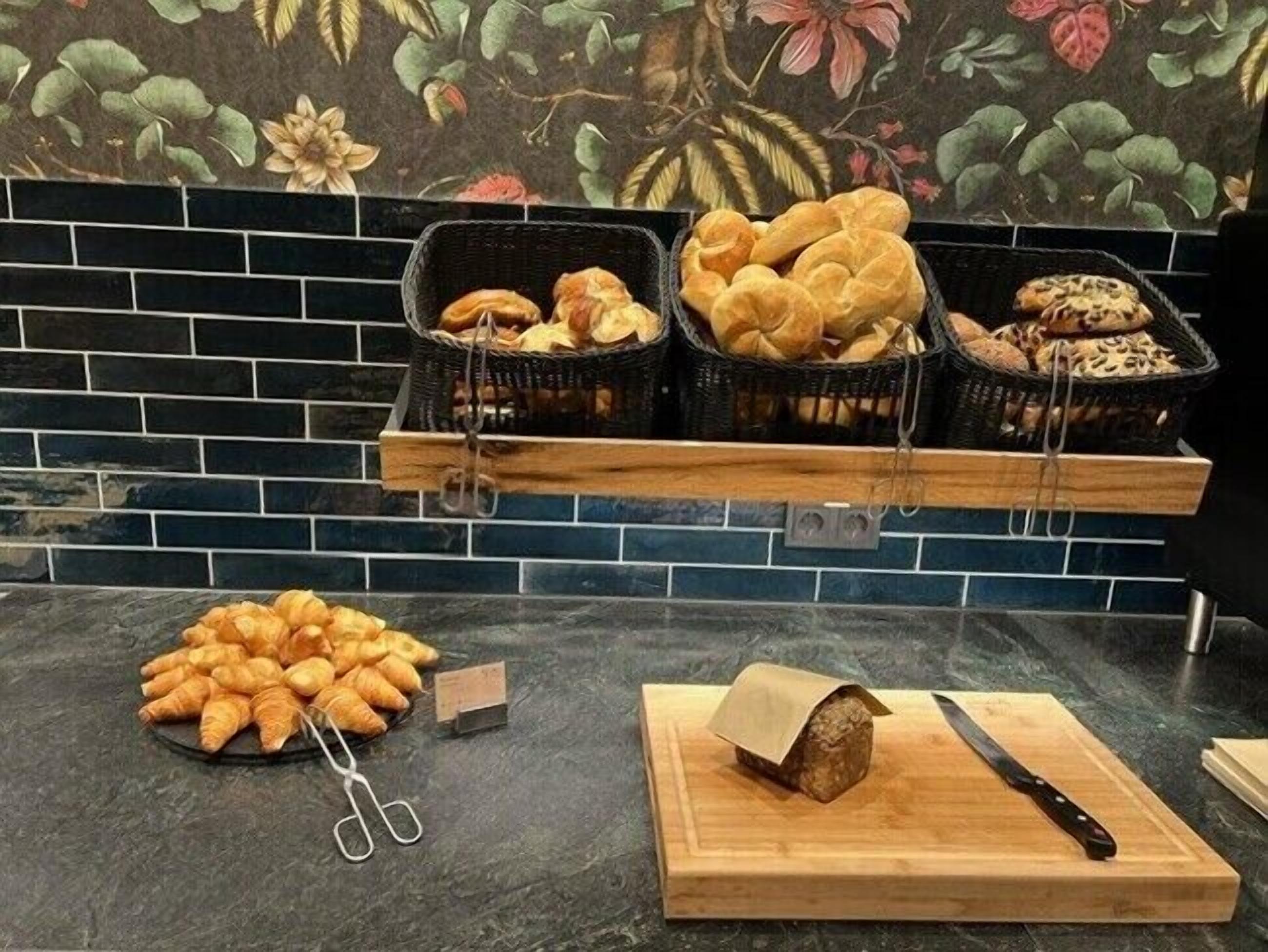 A bakery display with various baked goods, including croissants and bread, on a kitchen counter.