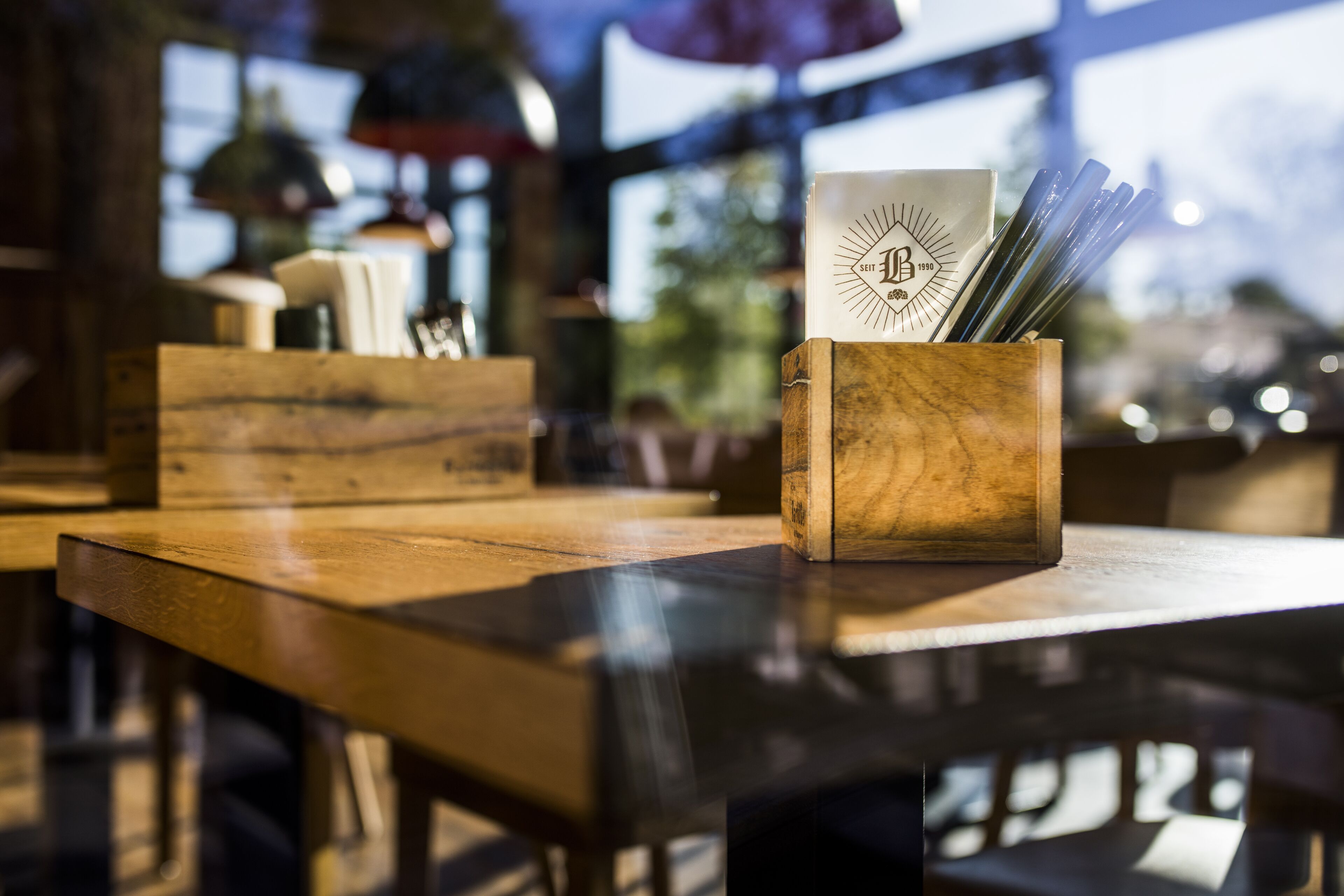 A wooden table with a menu holder containing a menu and chopsticks.