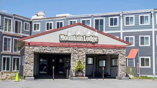 Un edificio con un letrero que dice "Mountain Lodge" y fachada de piedra.