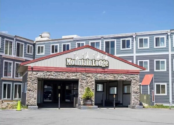 Mountain Lodge features a stone facade and a red roof, with a welcoming entrance and a small planter.