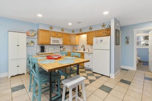 A kitchen with wooden cabinets, a microwave, a refrigerator, and a dining area with a table and chairs.