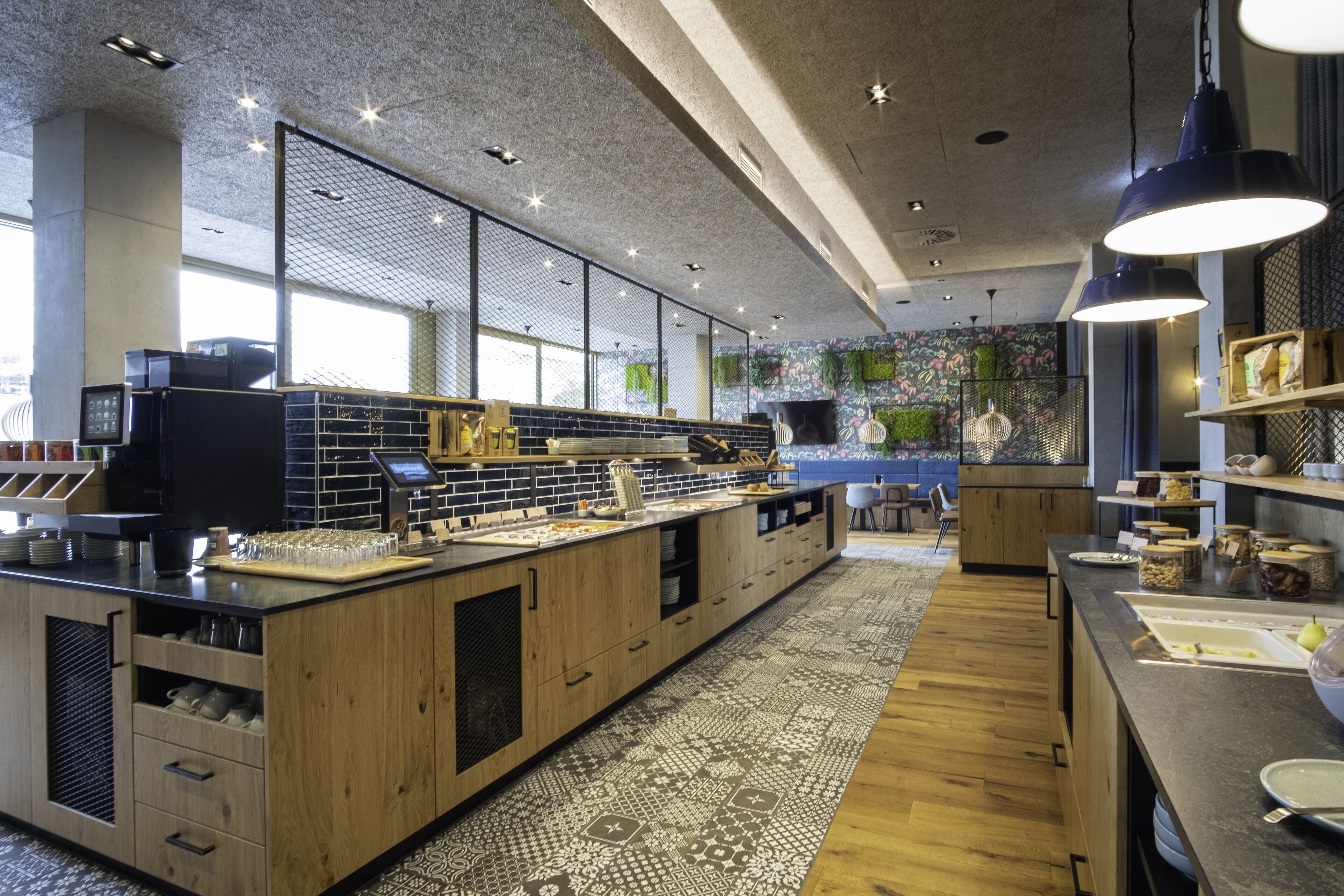 A modern kitchen with wooden cabinets, a black countertop, and a patterned rug.