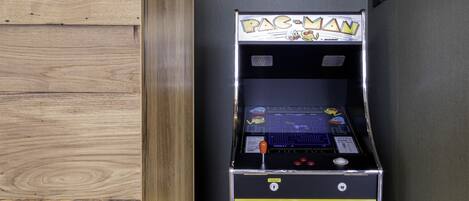 Una máquina arcade de Pac-Man en una habitación con paneles de madera y una pared gris.