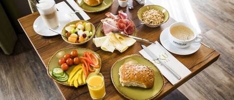 A breakfast table with various food items, a cup of coffee, and a plate of eggs.