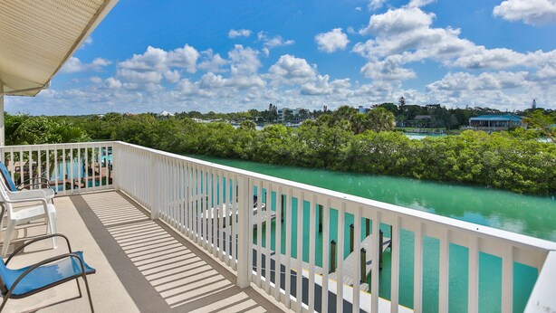 Een balkon met witte reling dat uitkijkt over een turquoise rivier, omringd door weelderige begroeiing.