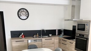 Eine moderne Küche mit Esstisch, Stühlen, Spüle, Mikrowelle und einer Uhr an der Wand.