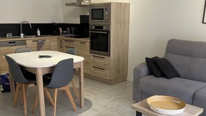 Eine moderne Küche mit Essbereich, einem grauen Sofa und einem kleinen Holztisch mit Tablett.