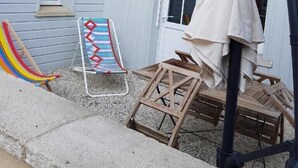 Ein Garten mit einer Ziegelmauer, einer Holzdiele und einer bunten Rutsche, sowie einem beigen Sonnenschirm.