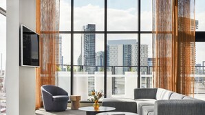 A modern living room with a large window, a flat-screen TV, and a sofa. - Oakwood Premier Melbourne (Melbourne)