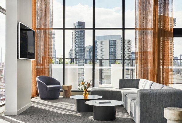 Een moderne woonkamer met een groot raam, een flatscreen televisie en een bank.