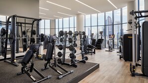 A modern gym with various weightlifting equipment, large windows, and a city view. - Oakwood Premier Melbourne (Melbourne)