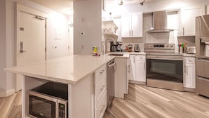 Eine moderne Küche mit weißen Schränken, Edelstahlgeräten und einem eingebauten Backofen.