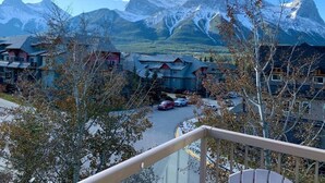 A mountain resort with multiple buildings, a parking area, and a view of snow-capped peaks. - Top-Floor Condo | 2BR + AC with Mountain Views (Canmore)