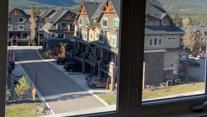 A residential area with houses, a road, and mountains in the background. - Top-Floor Condo | 2BR + AC with Mountain Views (Canmore)