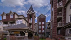 A hotel entrance with a covered walkway, multiple-story buildings, and a clear sky. - Mountain View/Full Kitchen/BBQ/AC/King Bed (Canmore)