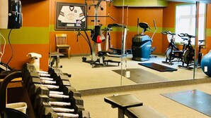 Un gimnasio con equipo de ejercicio, una televisión y un espejo.