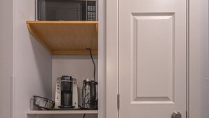Cocina compacta con microondas, cafetera y un refrigerador pequeño.