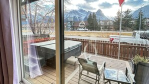 Eine Terrasse mit Gartenmöbeln, Blick auf ein Gebirge und eine Flagge.