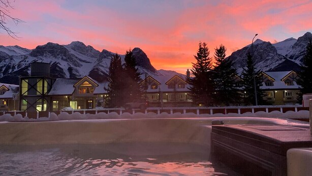 Ein Resort mit schneebedeckten Bergen, einem Pool und mehreren chaletenartigen Gebäuden.